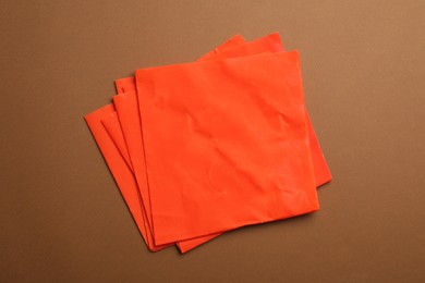 Photo of Red beeswax food wraps on brown background, top view
