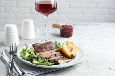 Photo of Delicious roasted beef meat, caramelized pear and greens served on light table. Space for text