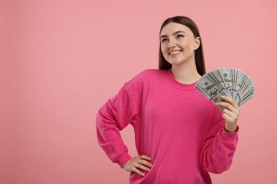 Photo of Happy woman with dollar banknotes on pink background, space for text