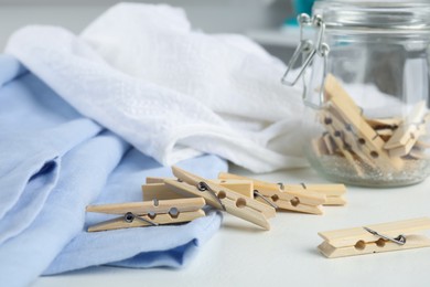 Many wooden clothespins and garments on white table indoors