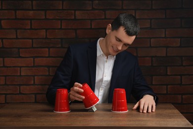 Photo of Shell game. Man showing dollar banknote under cup at wooden table