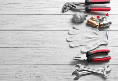 Flat lay composition with plumber's tools and space for text on wooden background