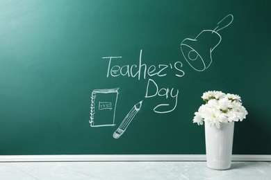 Photo of Green chalkboard with inscription TEACHER'S DAY and vase of flowers on grey stone table. Space for text