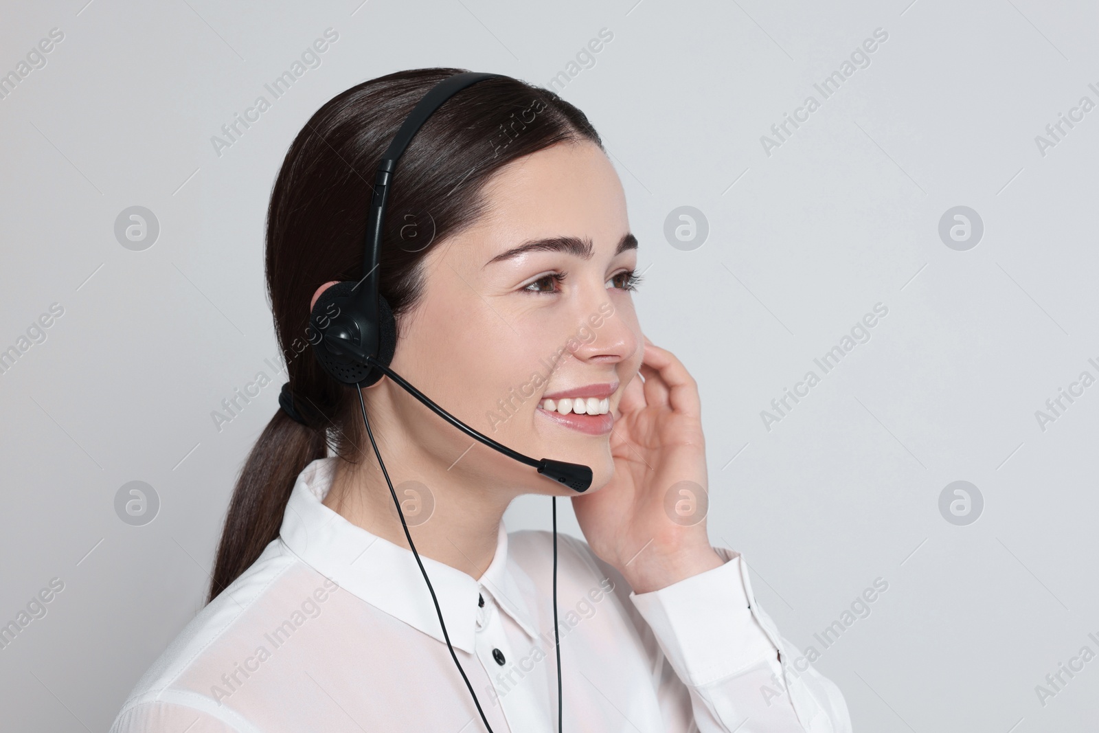 Photo of Hotline operator with modern headset on light grey background, space for text. Customer support