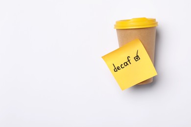 Photo of Note with word Decaf and checkbox attached to takeaway coffee cup on white background, top view. Space for text