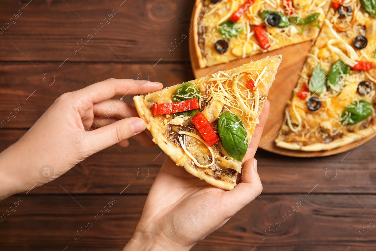 Photo of Woman holding delicious homemade pizza slice on wooden background