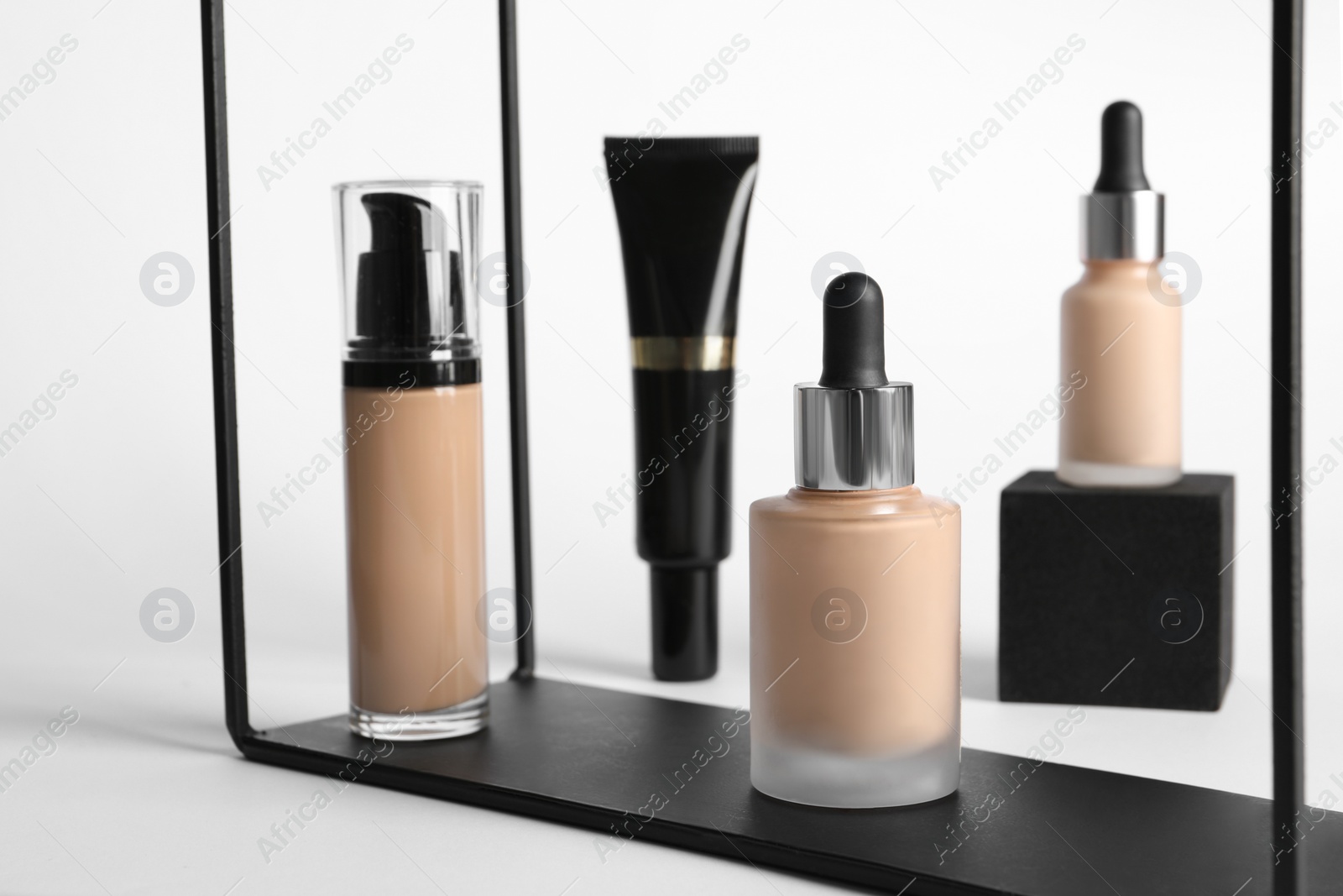Photo of Stylish presentation of bottles and tube with skin foundation on white background. Makeup product