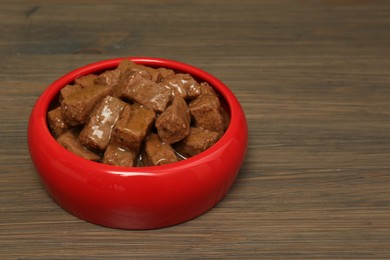 Photo of Wet pet food in feeding bowl on wooden background, space for text