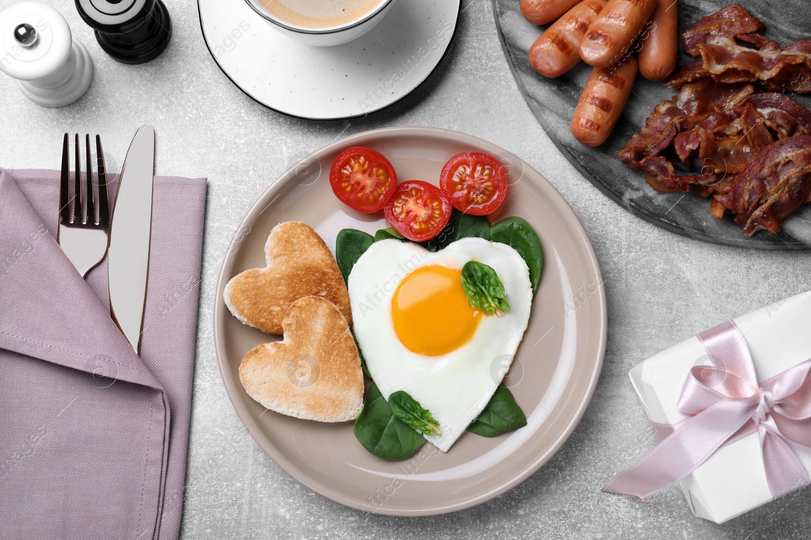 Photo of Romantic breakfast with heart shaped toasts and fried egg on grey table, flat lay. Valentine's day celebration