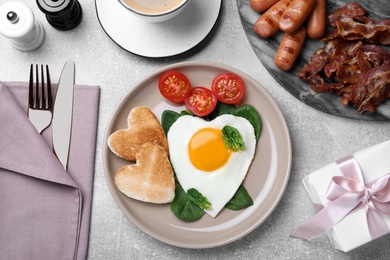 Romantic breakfast with heart shaped toasts and fried egg on grey table, flat lay. Valentine's day celebration