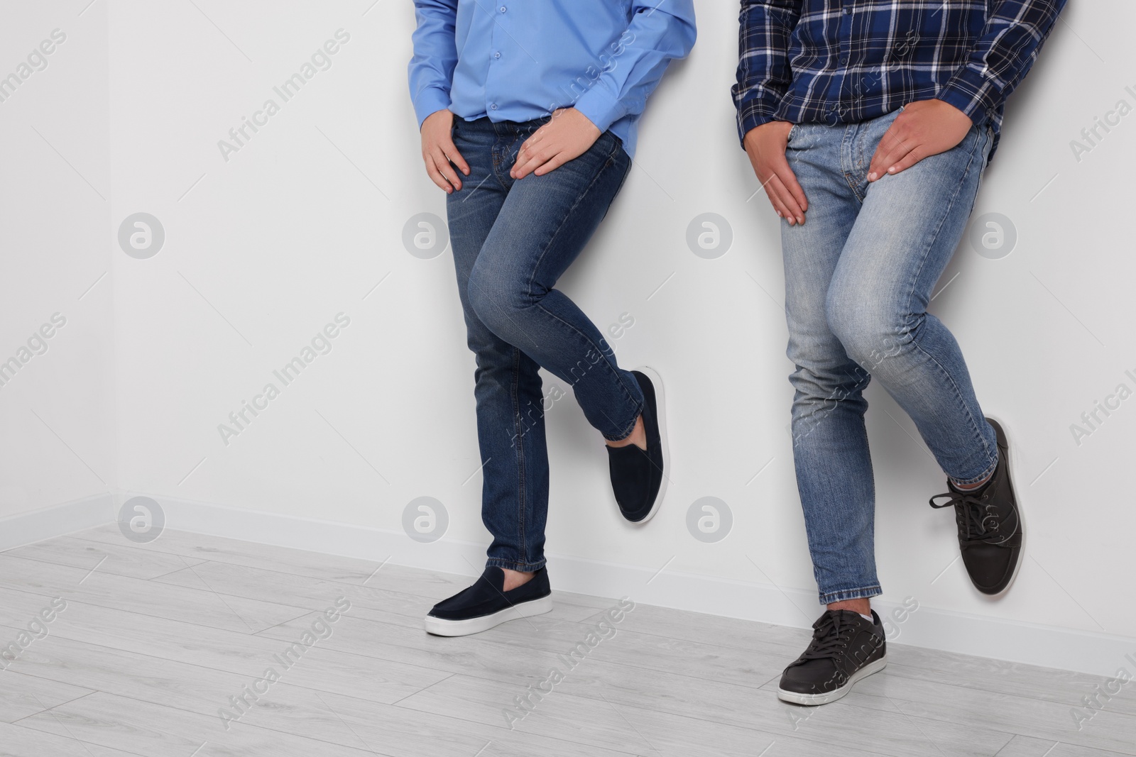 Photo of Men in stylish jeans near white wall indoors, closeup. Space for text