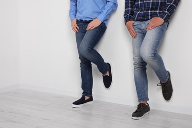 Photo of Men in stylish jeans near white wall indoors, closeup. Space for text