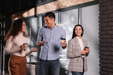 Photo of Group of coworkers talking during coffee break in office