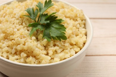 Photo of Delicious bulgur with parsley in bowl on table, closeup