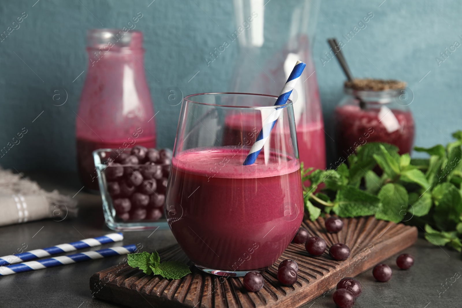 Photo of Composition with glass of acai juice and fresh berries on dark table