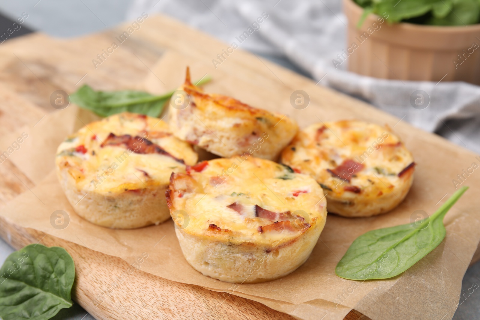 Photo of Delicious egg muffins with cheese and bacon on wooden board, closeup. Space for text