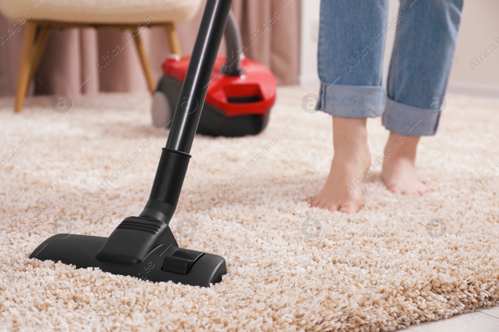 Photo of Woman cleaning carpet with vacuum cleaner at home, closeup. Space for text