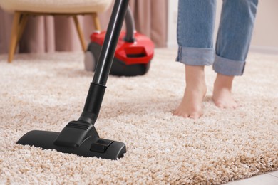 Woman cleaning carpet with vacuum cleaner at home, closeup. Space for text