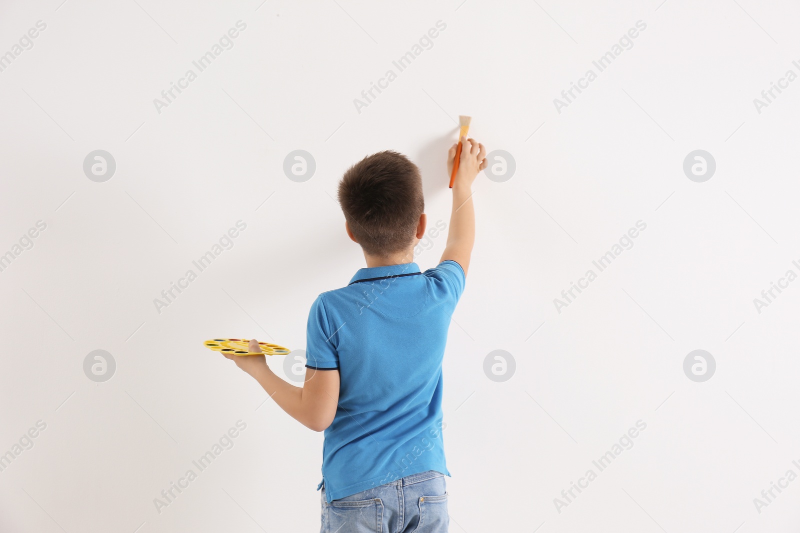 Photo of Little child painting on white wall indoors