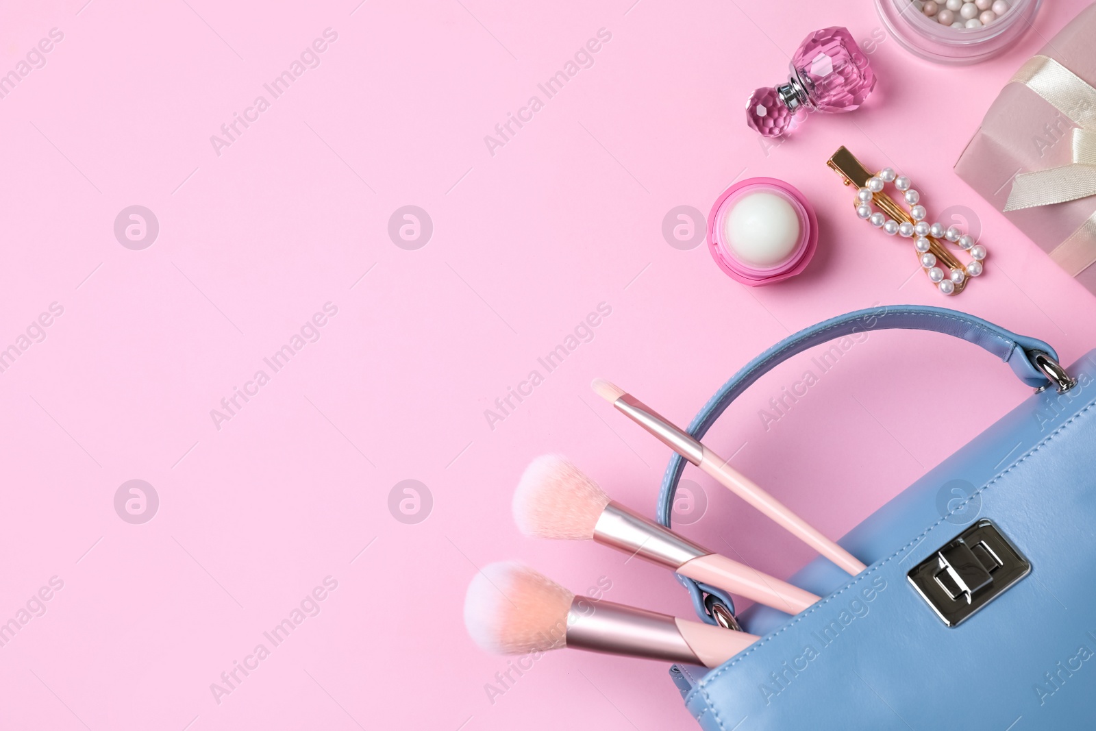 Photo of Flat lay composition with women's bag, accessories and makeup products on pink background. Space for text