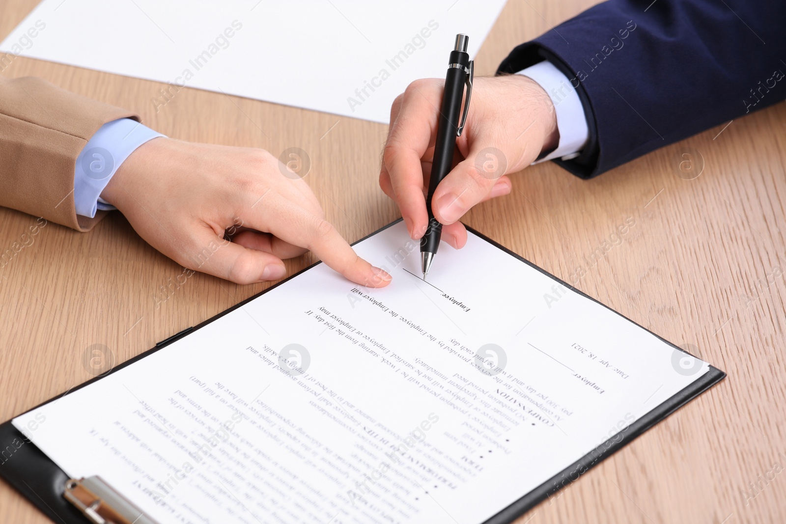 Photo of Businesspeople signing contract at wooden table, closeup of hands