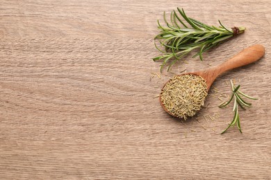 Spoon with dry rosemary and fresh twigs on wooden table, flat lay. Space for text