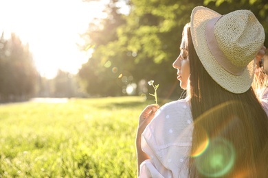 Photo of Young woman with flower outdoors on sunny day, space for text