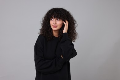 Photo of Young woman in stylish black sweater on light grey background