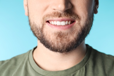 Young man with healthy teeth on color background, closeup