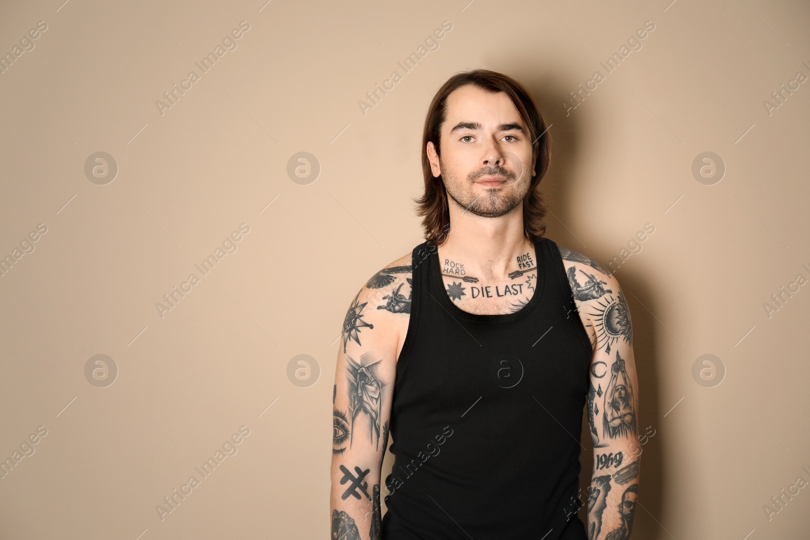 Photo of Young man with tattoos on body against beige background