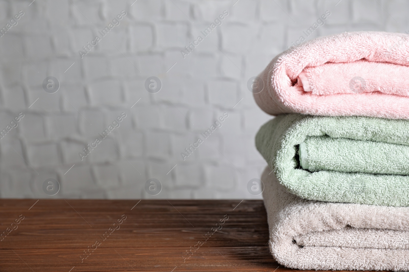 Photo of Stack of clean bath towels on wooden table. Space for text