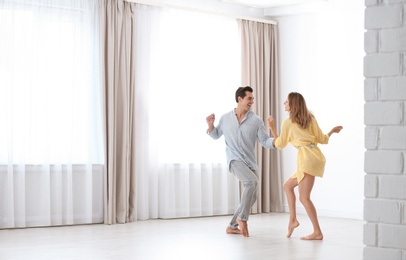 Photo of Beautiful young couple dancing in room at home
