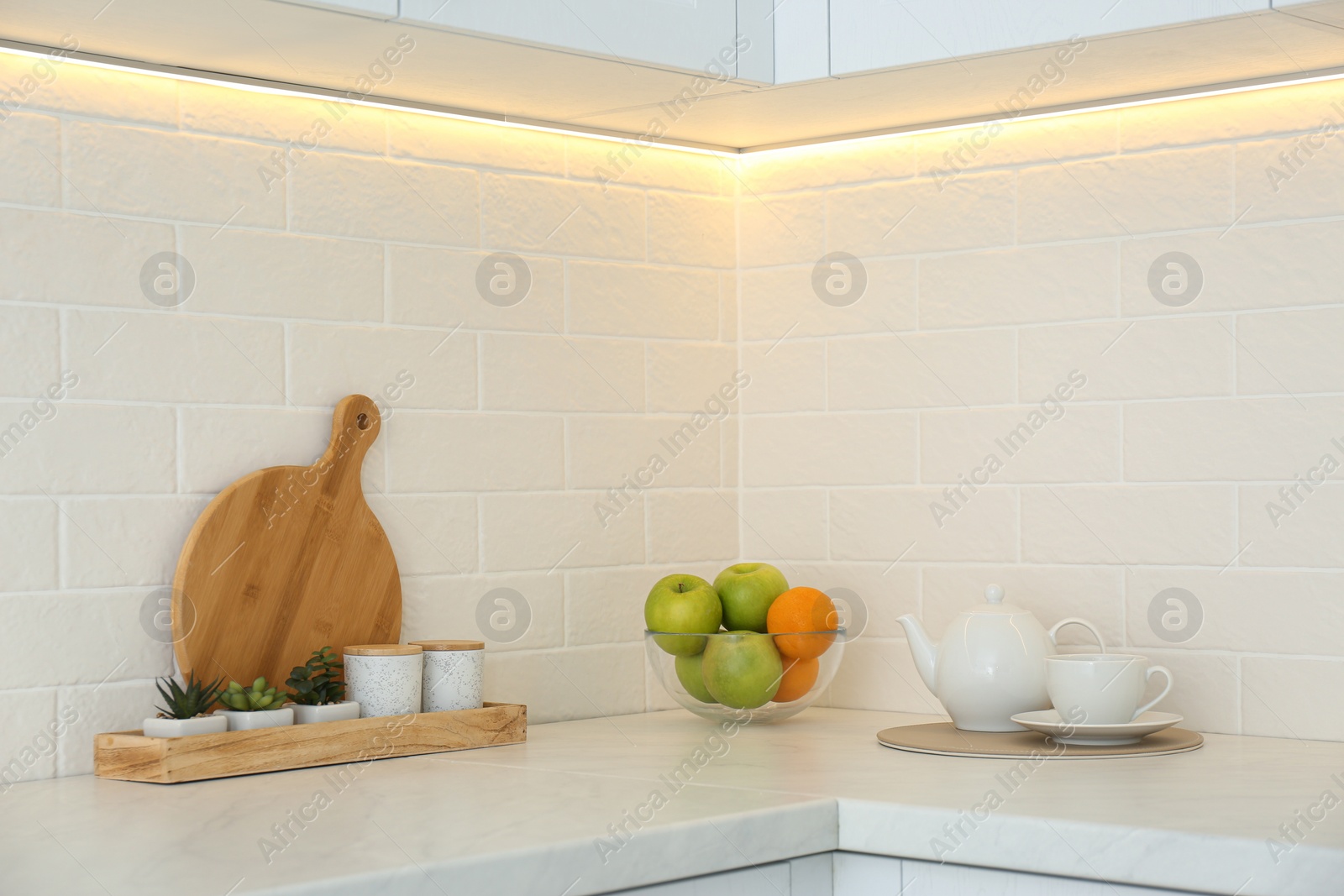 Photo of Fresh fruits and teapot on countertop in modern kitchen