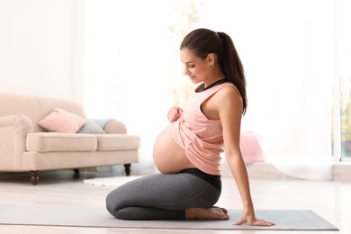 Photo of Young pregnant woman in fitness clothes at home