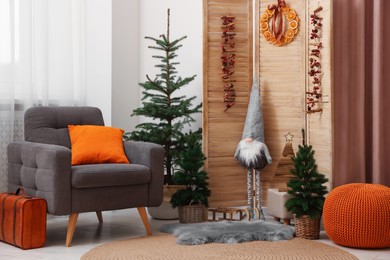 Photo of Beautiful Christmas themed photo zone with trees, dwarf and armchair in room