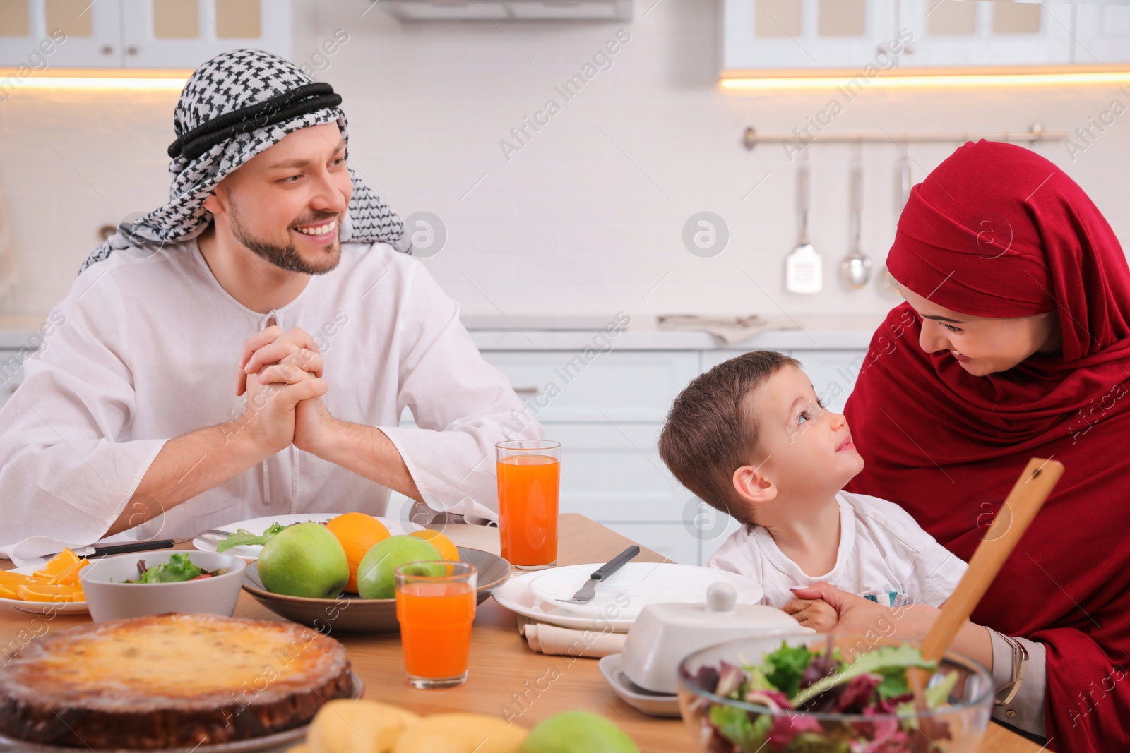 Photo of Happy Muslim family eating together at table in kitchen