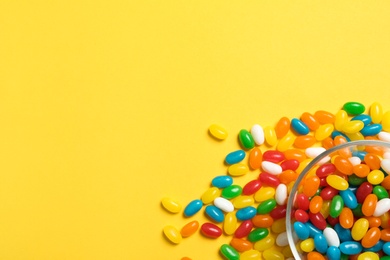 Photo of Bowl of jelly beans on color background, top view. Space for text