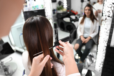 Professional hairdresser working with client in beauty salon, closeup