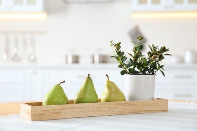 Photo of Fresh ripe pears and plant on table in kitchen