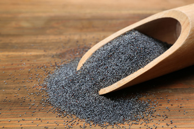 Poppy seeds in scoop on wooden table, closeup