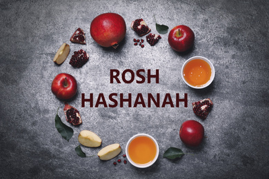 Image of Frame of honey, apples and pomegranates on grey table, flat lay. Rosh Hashanah holiday