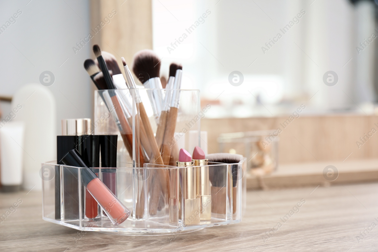 Photo of Organizer with cosmetic products for makeup on table near mirror. Space for text