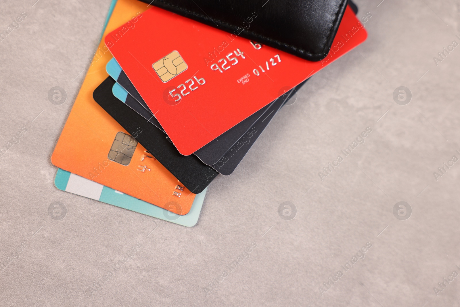 Photo of Pile of different credit cards on grey table, top view. Space for text