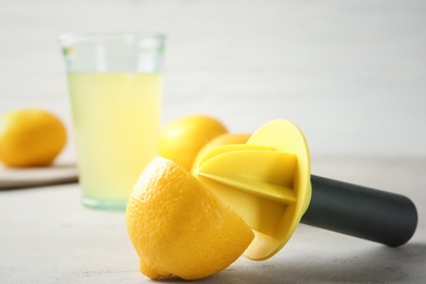 Photo of Fresh ripe lemon and reamer on table