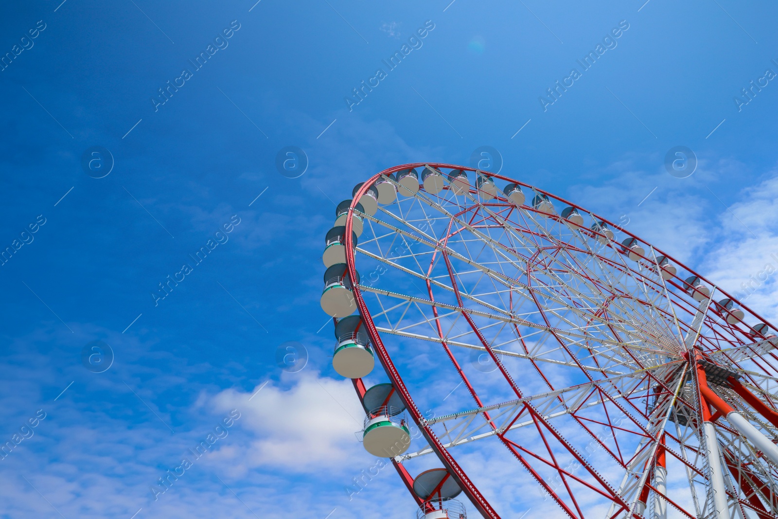 Photo of Beautiful large Ferris wheel against blue sky, low angle view