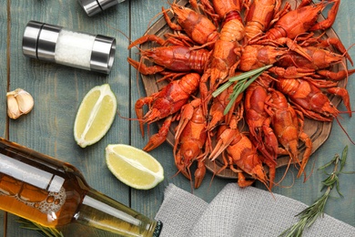 Photo of Flat lay composition with delicious red boiled crayfishes and beer on wooden table