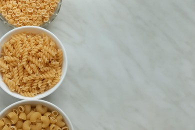 Different types of pasta on white marble table, flat lay. Space for text