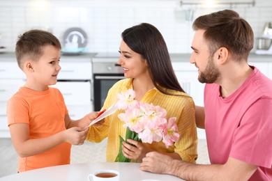 Photo of Father and son congratulating mom in kitchen. Happy Mother's Day