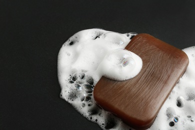Photo of Soap bar and foam on black background