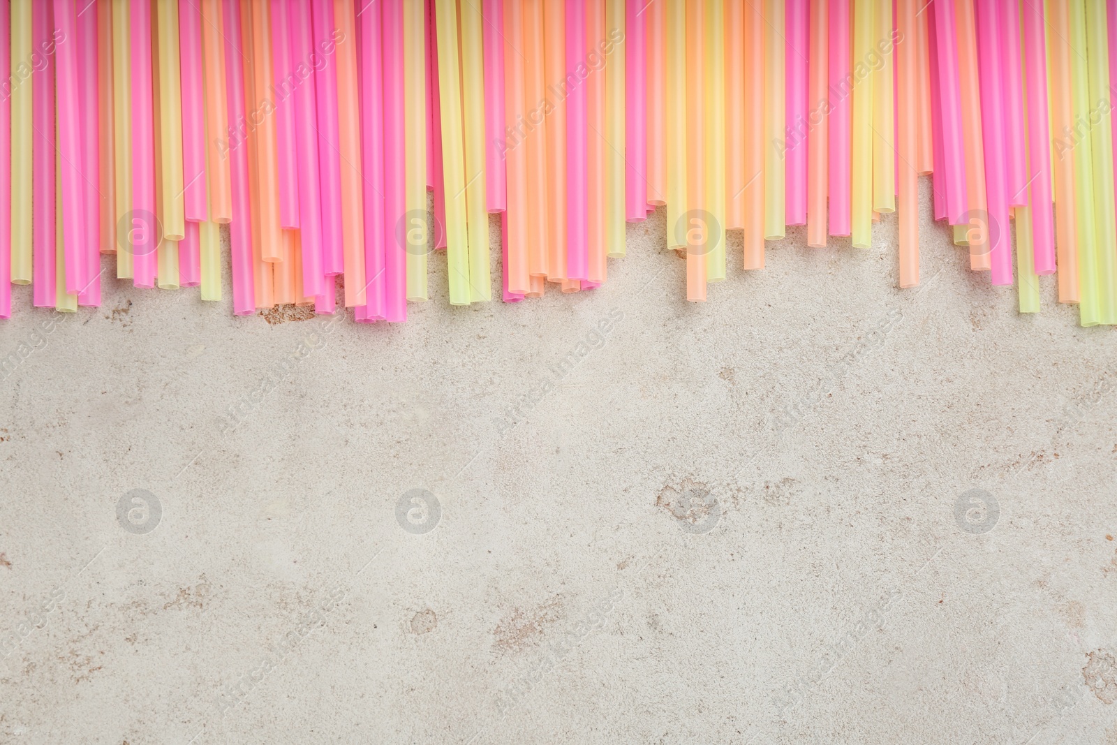 Photo of Colorful plastic drinking straws on grey stone table, flat lay. Space for text